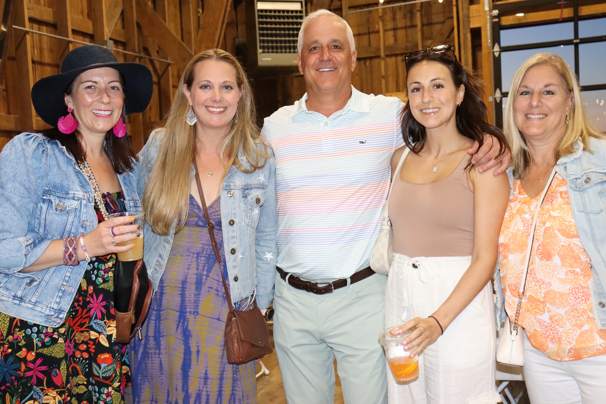 A group of 4 women and 1 man posing together in a picture in a barn like setting for the Taste of David's Refuge event.