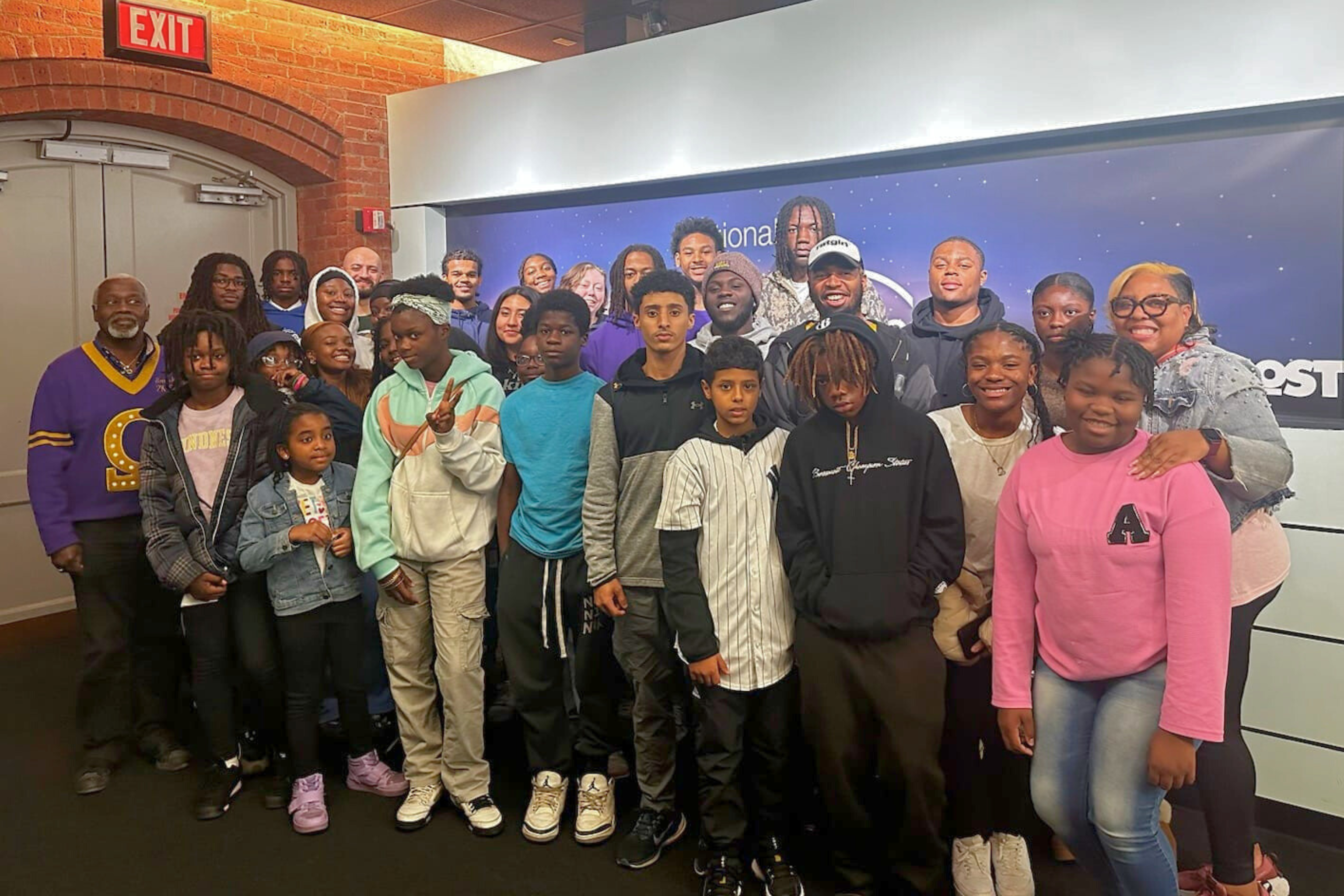 A large group of mostly African American youth and some adults who are members of Syracuse STEM NSBE posing for a group picture at The Most.