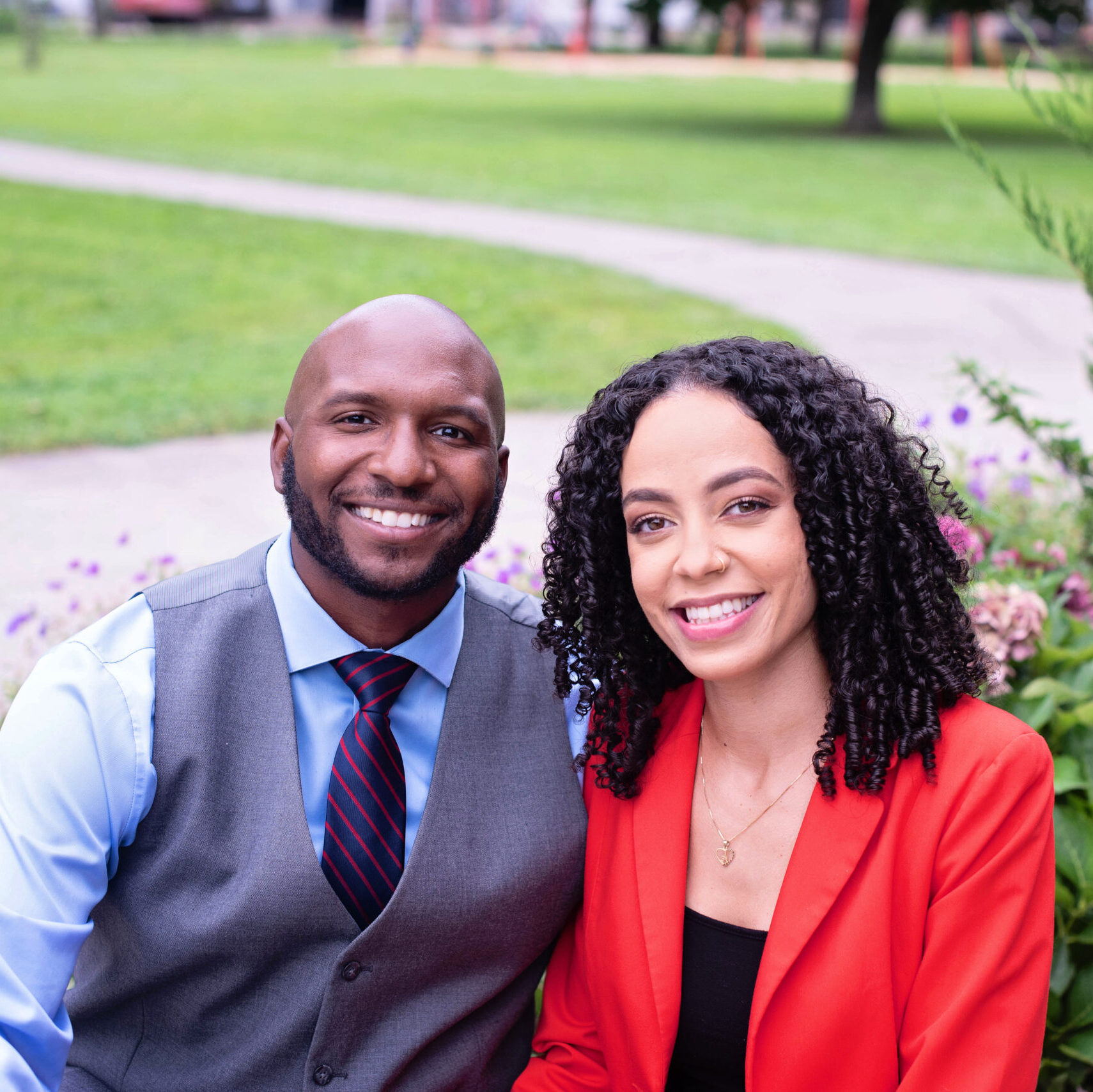 Professional photo of Demitrius McNeil and Arlaina-Harris from Our Glass Consulting - both in professional attire with green park in background.